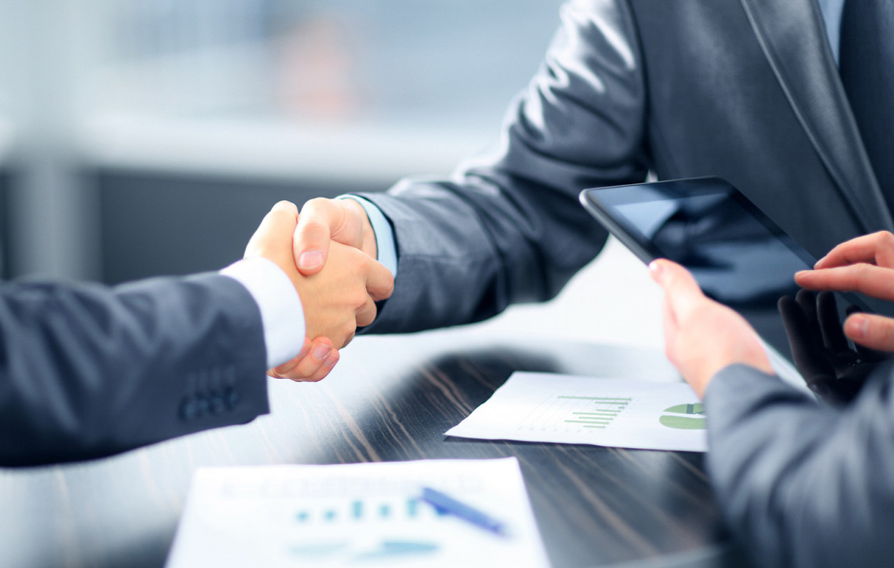 Business people shaking hands in office - Imagebild: Geschäftspartner beim Händeschütteln